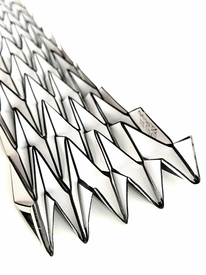 A close-up view of a geometric, zigzag origami structure from the 3Dtachables Collection, featuring interlocking black and white paper segments on a white background.