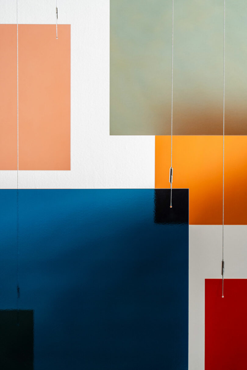 Abstract composition with overlapping colored rectangles in blue, orange, red, and beige tones, intersected by hanging silver cords against a white background, showcasing a modern 3form-inspired aesthetic.