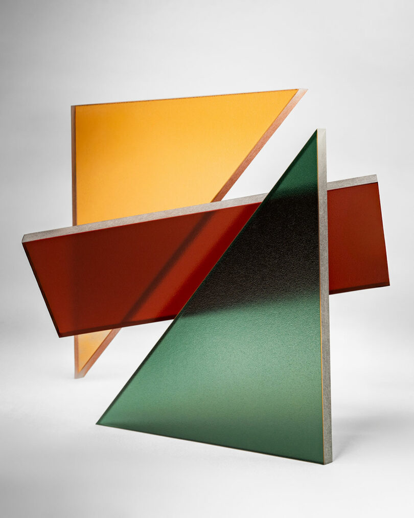 Three overlapping geometric panels—yellow, red, and green—arranged against a plain white background, create a modern abstract composition in the signature style of 3form.