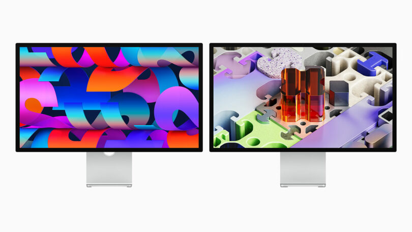 Two desktop monitors with silver stands display colorful abstract digital artwork on their screens against a plain white background.