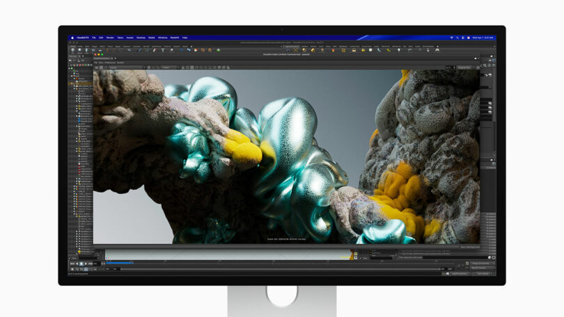 A computer monitor displays 3D modeling software with an abstract, organic digital sculpture featuring metallic and yellow textures.