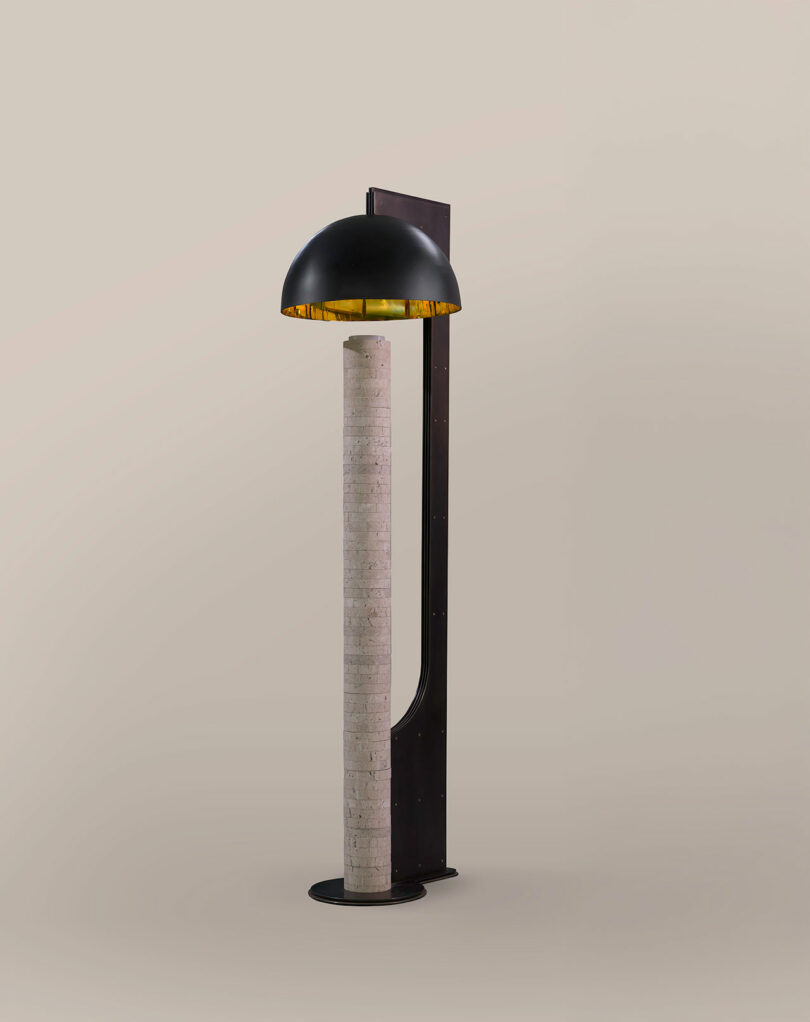 A modern ATRA floor lamp with a cylindrical stone base and a black metal dome-shaped shade, set against a plain light background.