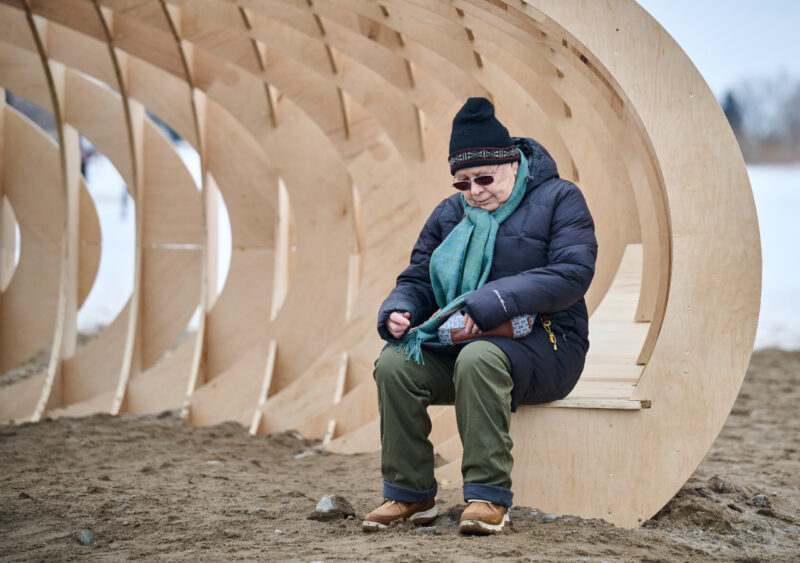 Person sits inside Crest art installation on Woodbine beach, Toronto