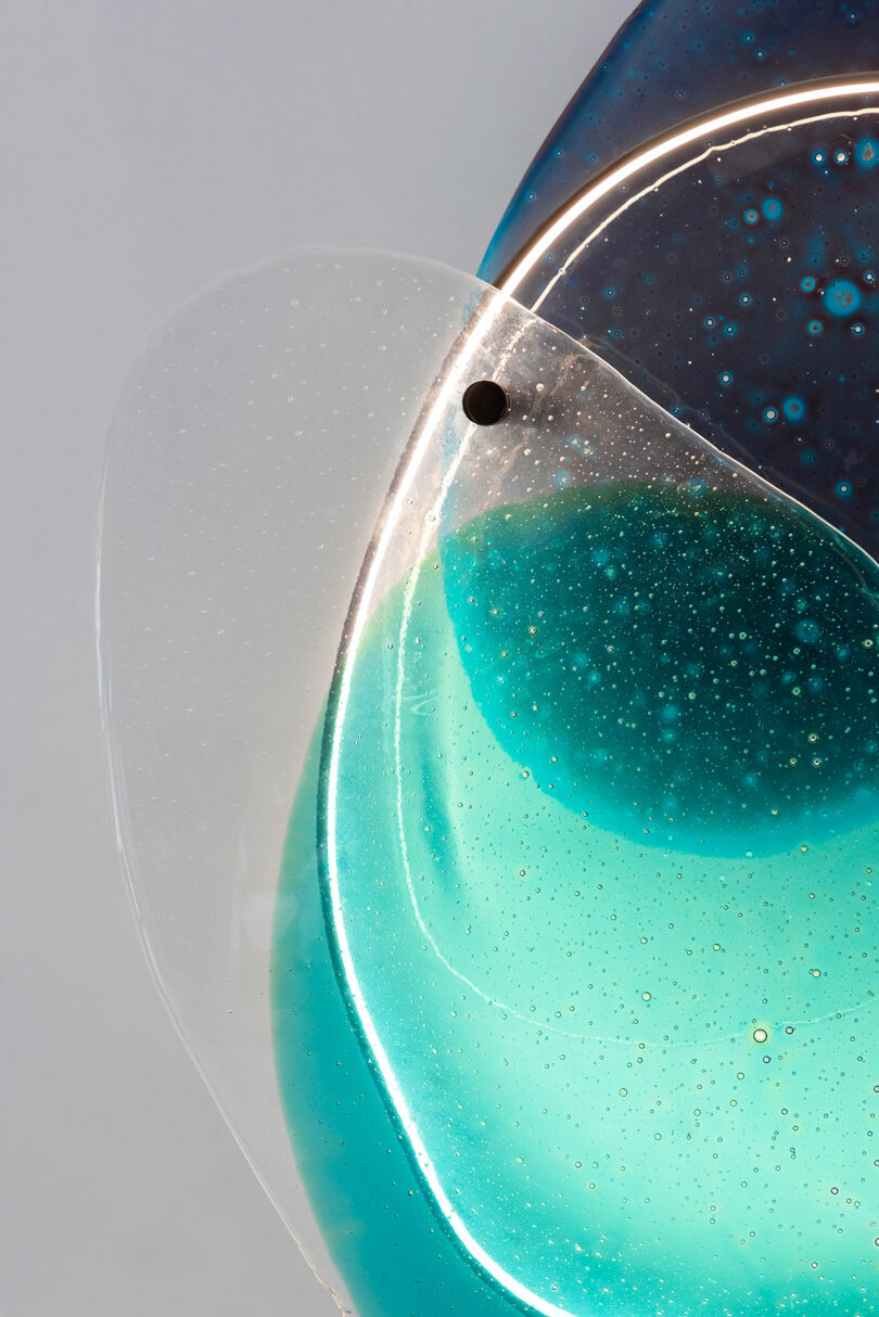 Close up of transparencies of blue glass on a white wall.