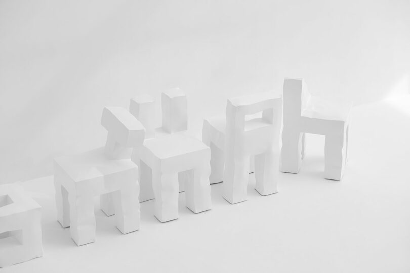 Five white, sculptural Kameh chairs with irregular, angular forms are arranged in a row against a plain white background.
