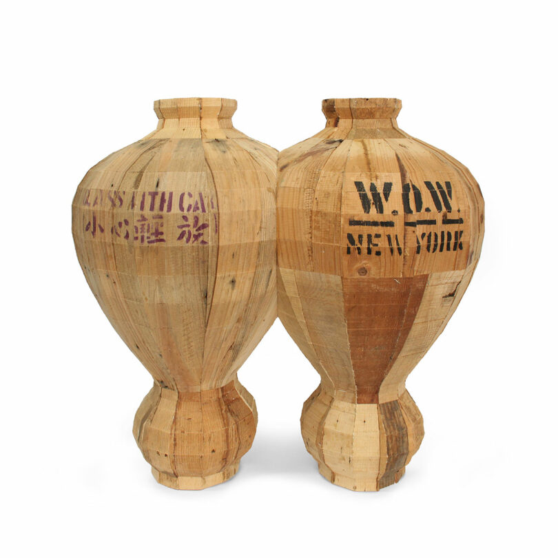 Two wooden vases by Vivian Chiu with visible seams, each featuring stenciled text in English and Chinese on their surfaces.