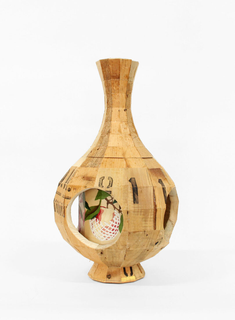 A wooden vase by Vivian Chiu with a narrow neck, wide body, and two large circular openings reveals a painted interior adorned with abstract colorful designs.