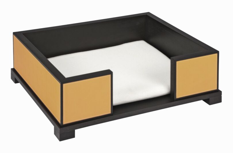 Rectangular black and tan pet bed with raised sides and a white cushion inside, set on four short legs