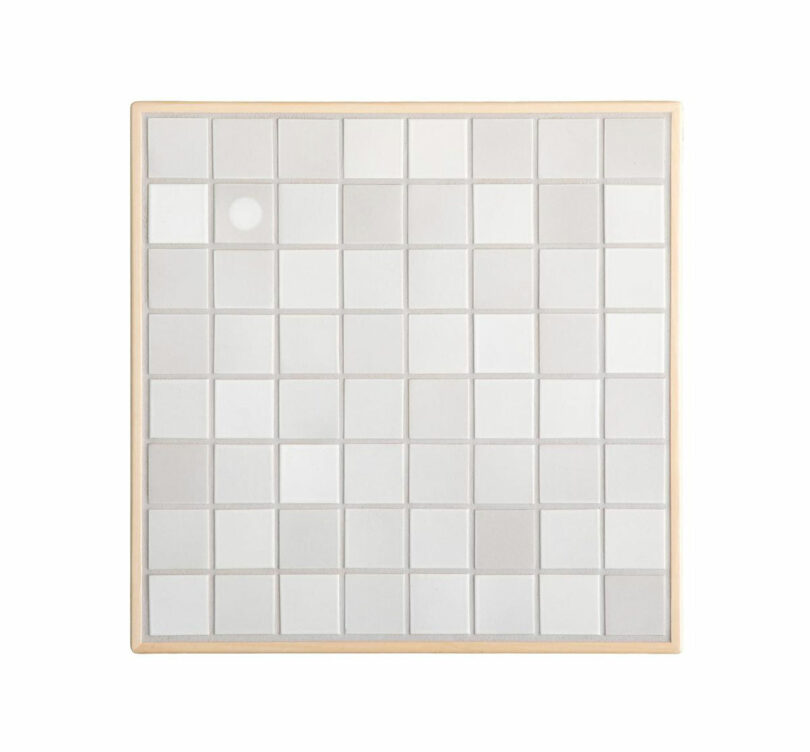 A square grid of 81 frosted glass tiles with a single solid white tile near the top left, framed by a light wooden border in the signature Artek style.