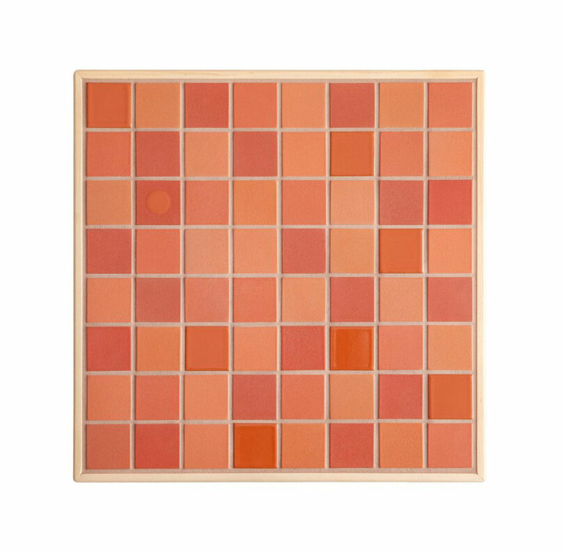 A square grid of red and orange tiles with various shades, framed in a light wooden border inspired by Artek’s iconic design aesthetic.