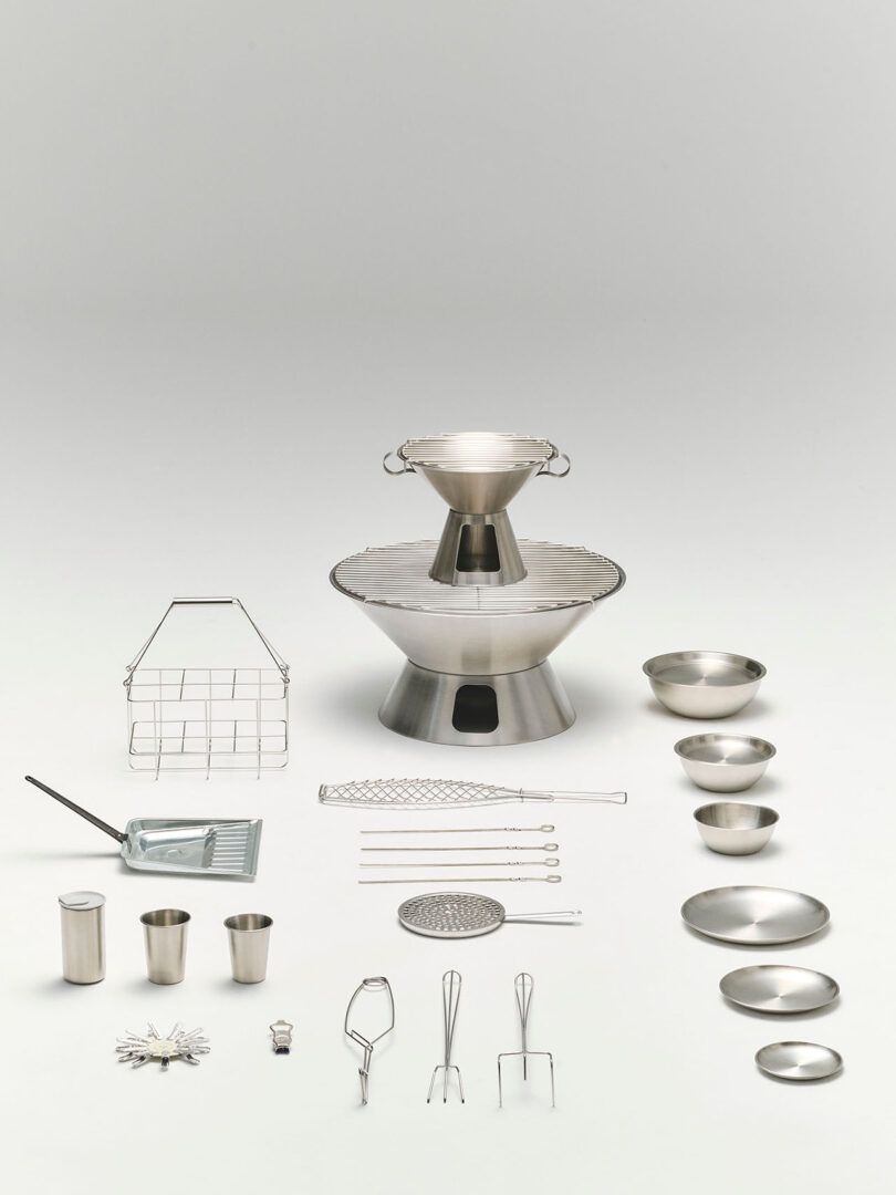 A set of stainless steel kitchen and grilling tools, utensils, bowls, and cookware arranged neatly on a plain white background.
