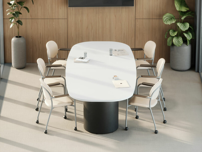 A modern conference room by KFi STUDiOS with a white oval table, six beige chairs, a wall-mounted screen, and plants in large pots by wood-paneled walls.