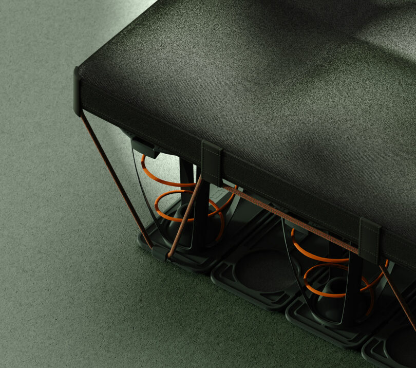 Close-up of a modern mattress showing exposed springs, a fabric top layer, and a plastic grid base on a solid-colored floor.