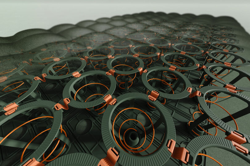 Close-up view of a patterned surface featuring interlocking black rings and orange coils, resembling a grid of mechanical or electronic components.