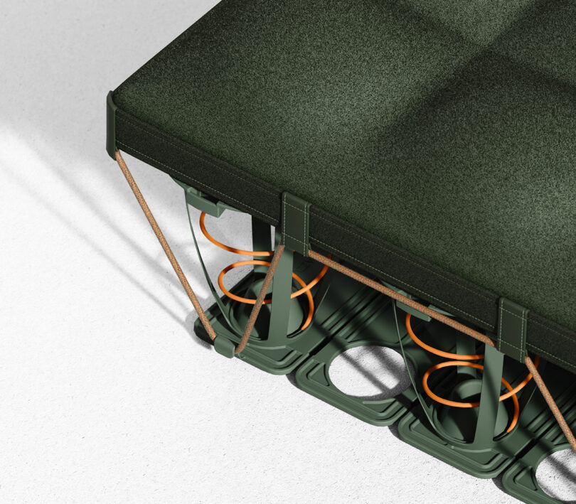 A close-up of a green mattress corner showing internal orange springs and support structure on a white surface.