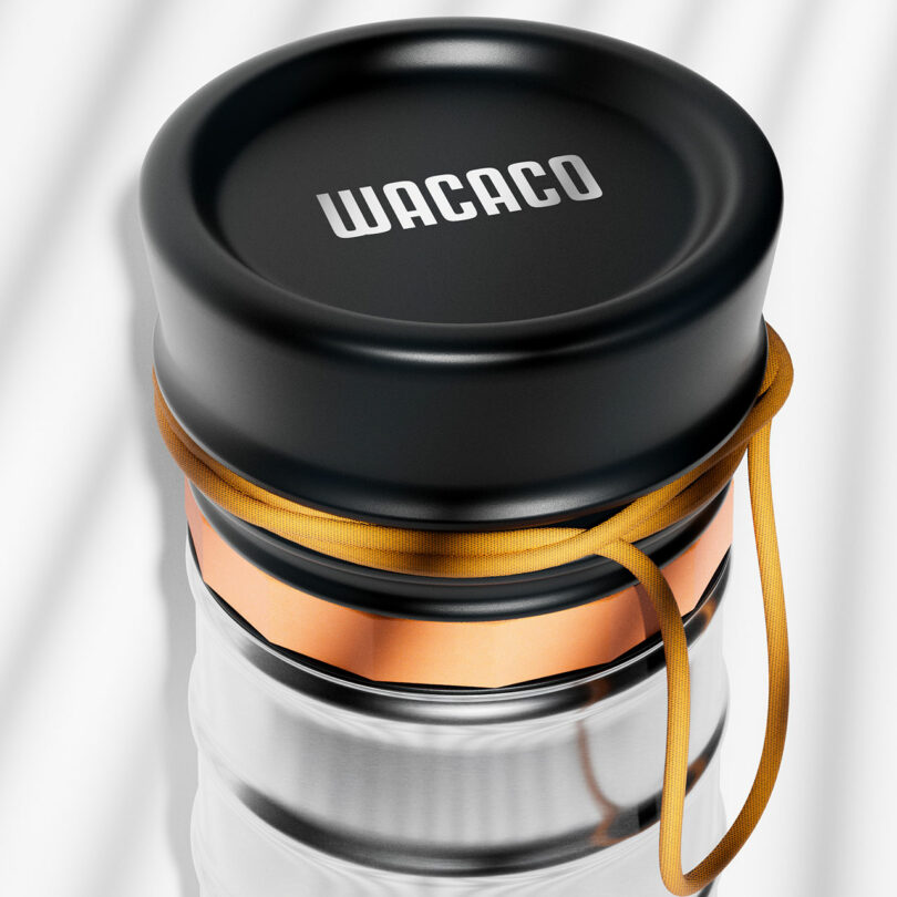 Close-up of a Wacaco-branded container with a black lid, orange band, and a yellow strap wrapped around it.