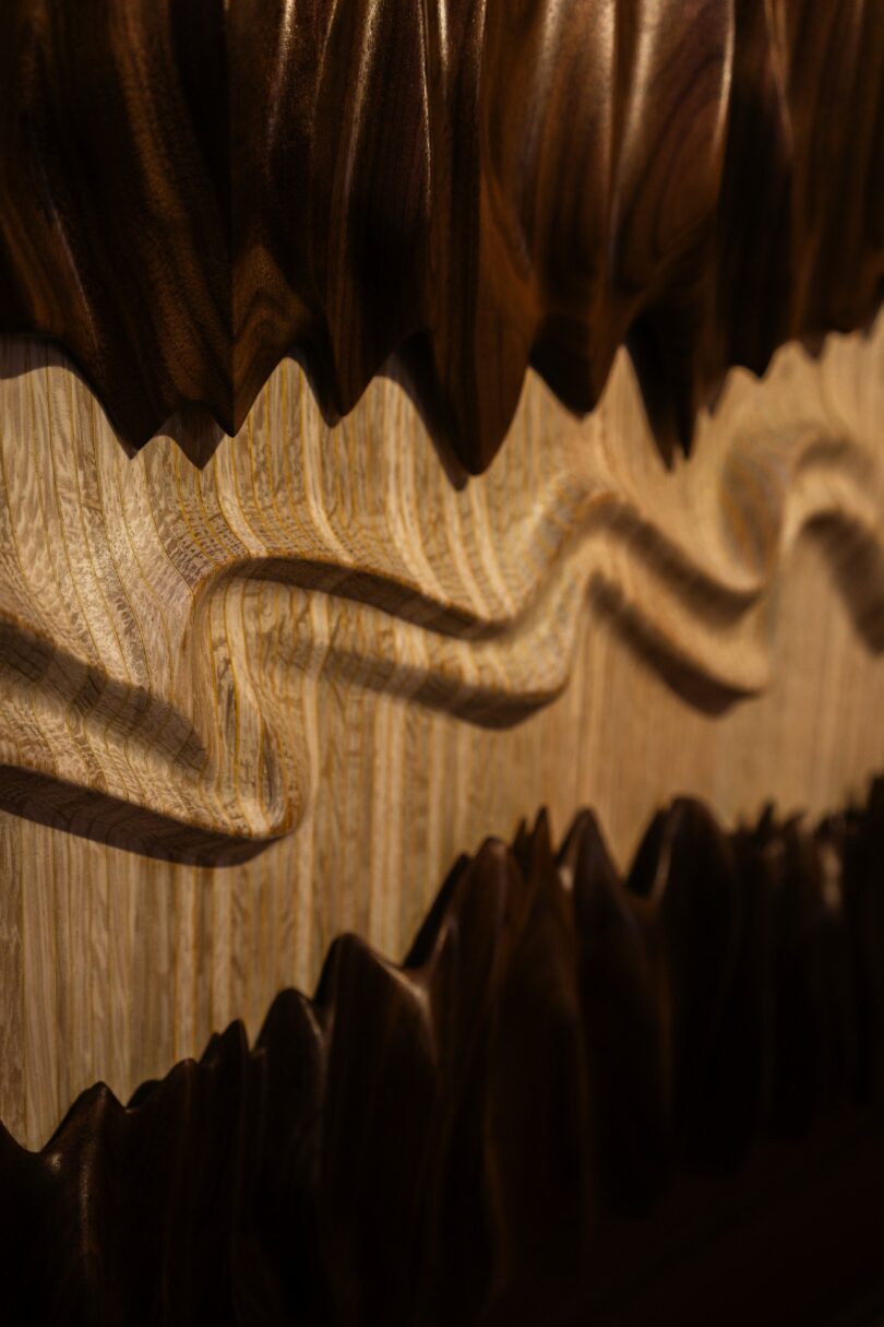 Close-up of a wooden surface with intricate, wavy, and jagged carved patterns in varying shades of brown