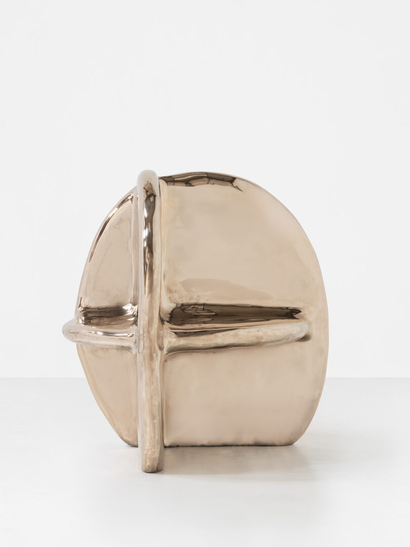 A polished, abstract bronze sculpture with rounded and intersecting forms, set against a plain white background.
