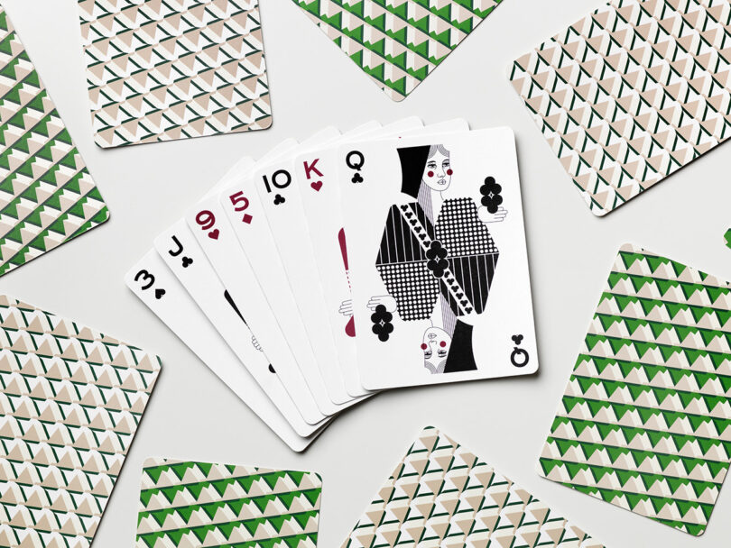 A fan of playing cards shows the 3, 9, 5, 10, and queen of spades surrounded by face-down cards with green and white geometric patterns.