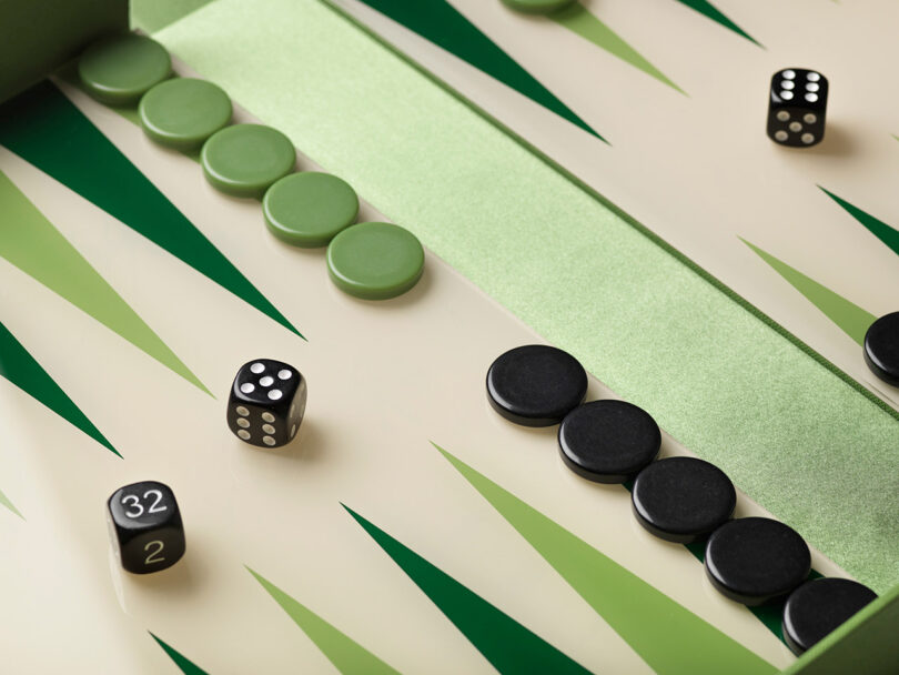 A close-up of a backgammon board with green and black checkers, two dice, and a doubling cube, all arranged on a green and cream patterned surface.