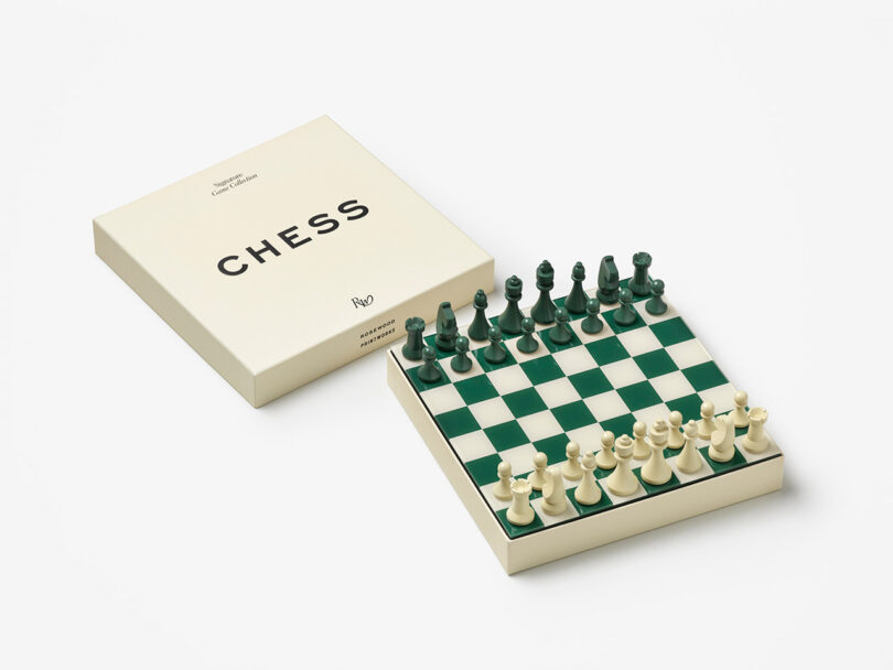 A chess set with a green and white checkered board is placed next to its cream-colored box labeled "CHESS." All pieces are arranged in their starting positions.
