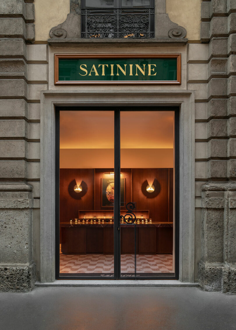 Storefront with a glass door and a sign reading "SATININE" above the entrance; warm lighting and a wooden interior are visible inside.