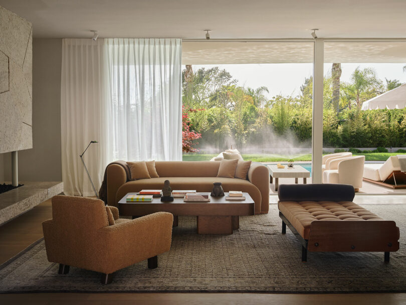 A modern living room with OSKLO-inspired neutral-toned furniture, a large window, and a view of a garden and swimming pool outside.