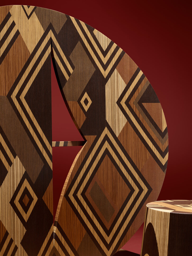 Wooden objects with geometric, diamond-shaped patterns in various shades of brown, set against a solid dark red background.