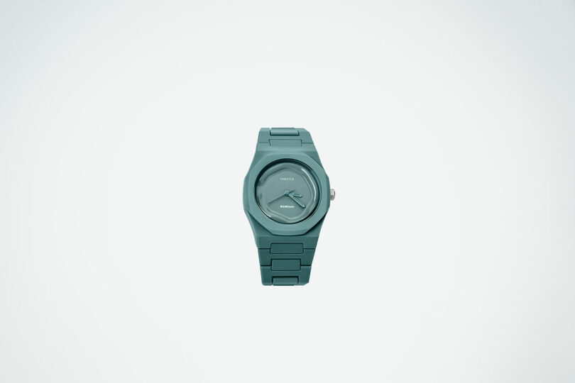 A teal wristwatch with a simple round face and matching teal band is centered on a plain white background.