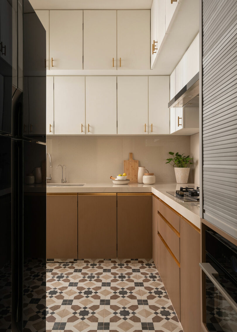Modern kitchen with white upper cabinets, brown lower cabinets, patterned tile floor, and minimal decor including a plant and cutting boards on the counter.