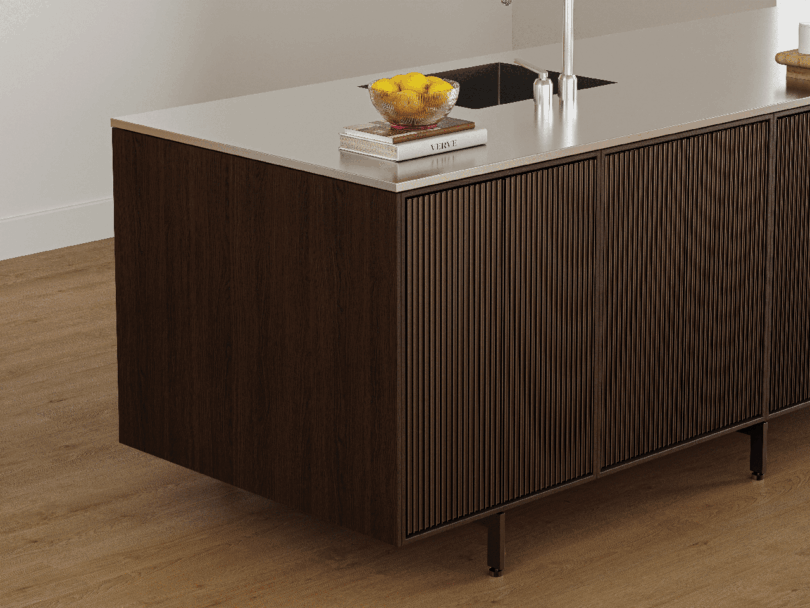 A modern Vipp kitchen island with a wood panel base, white countertop, books, a glass of water, and a white faucet, sits elegantly on a wooden floor.