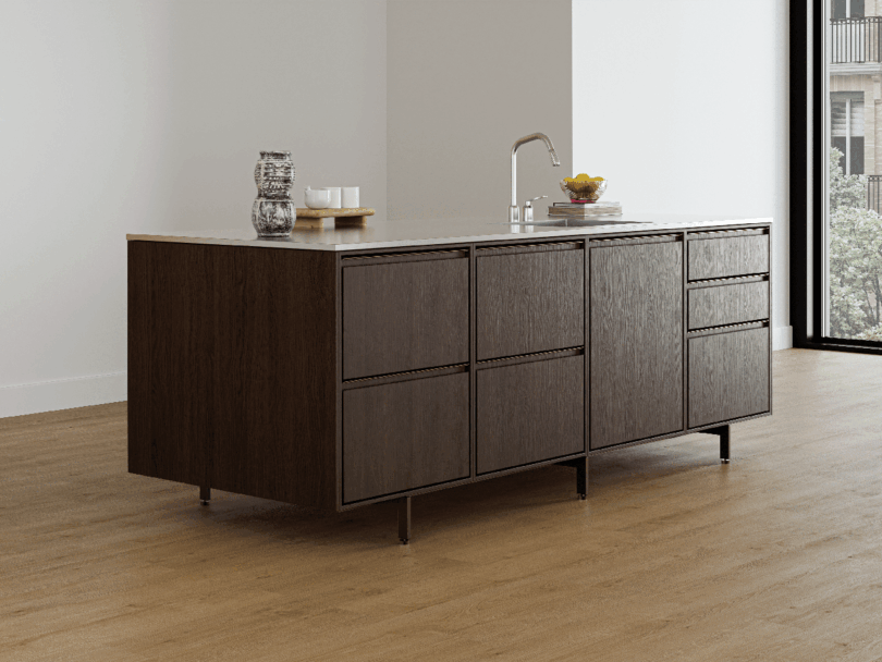 A modern kitchen island with dark wood cabinets, a Vipp sink, and a few items on the countertop, set on a light wood floor in a bright, minimalist room.